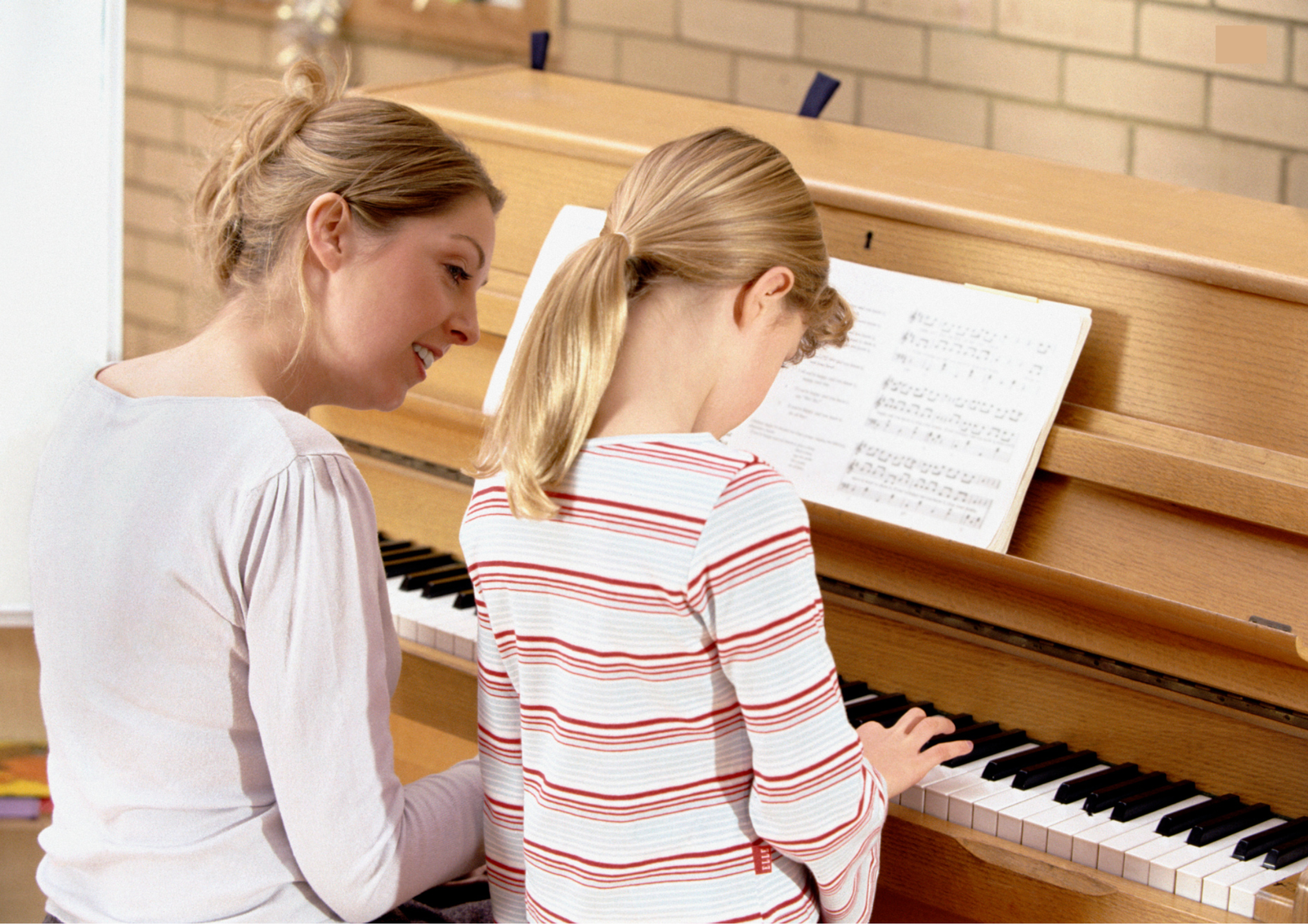Piano teacher is teaching piano to a girl during school hours